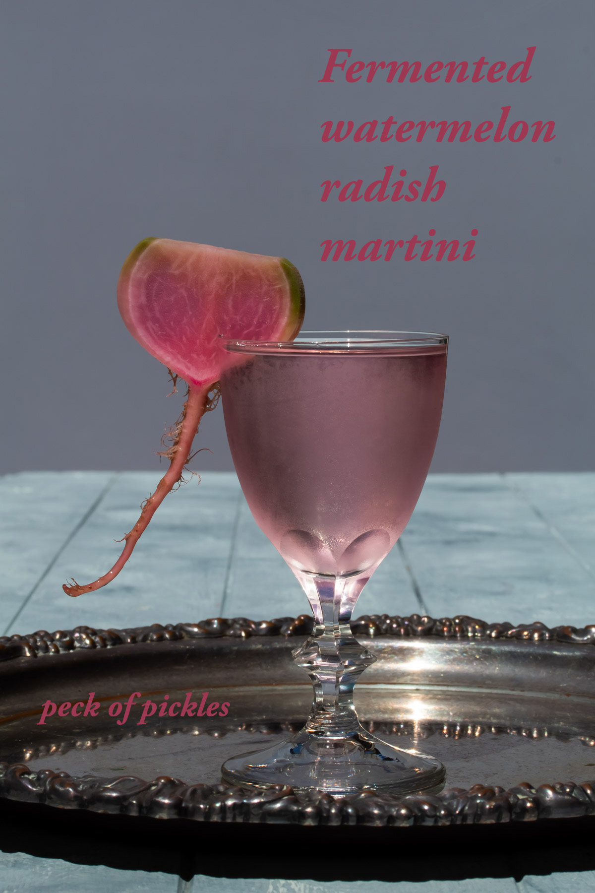 fermented watermelon radish martini on vintage silver tray with light purple background