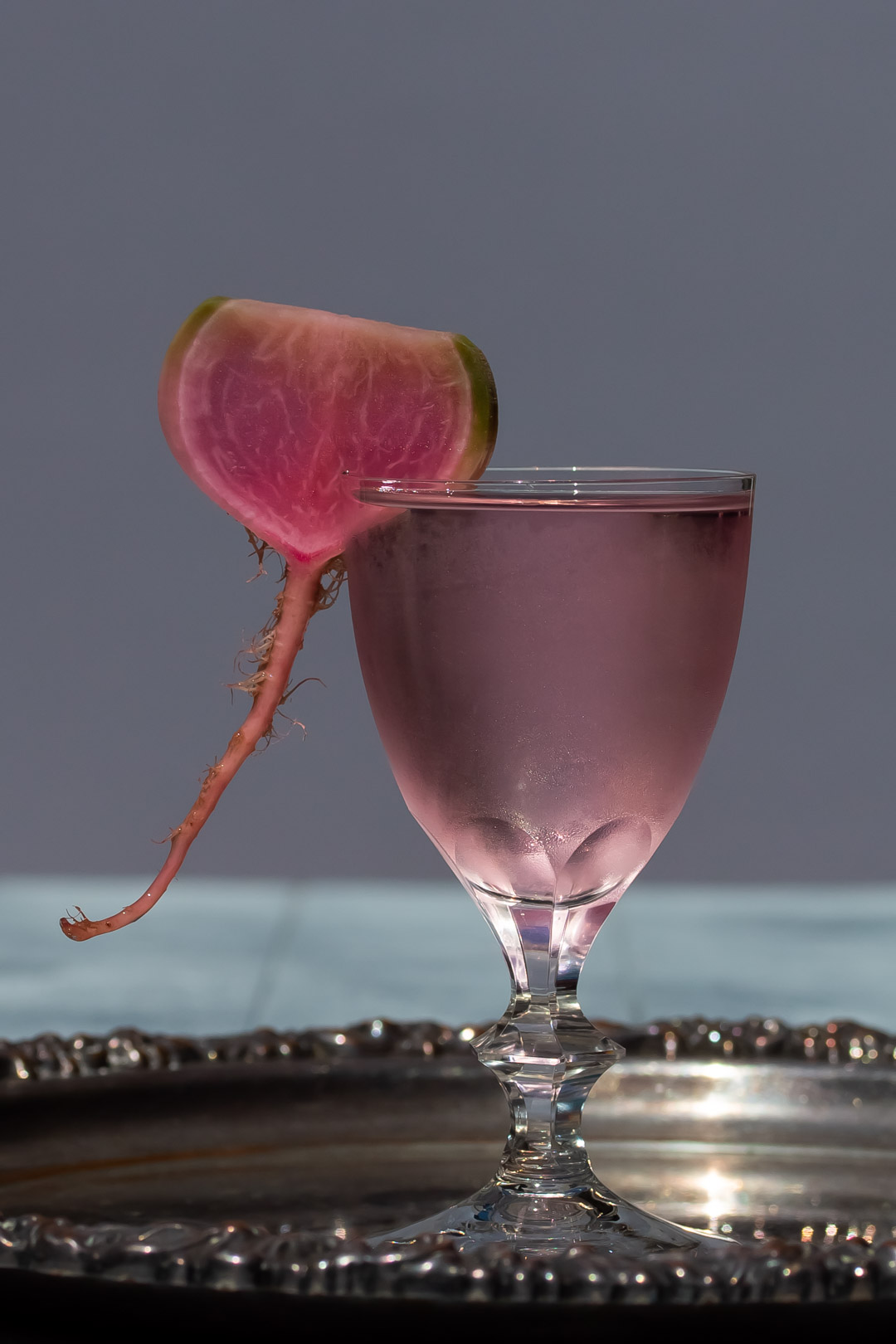 fermented watermelon radish martini on silver tray with blurred background