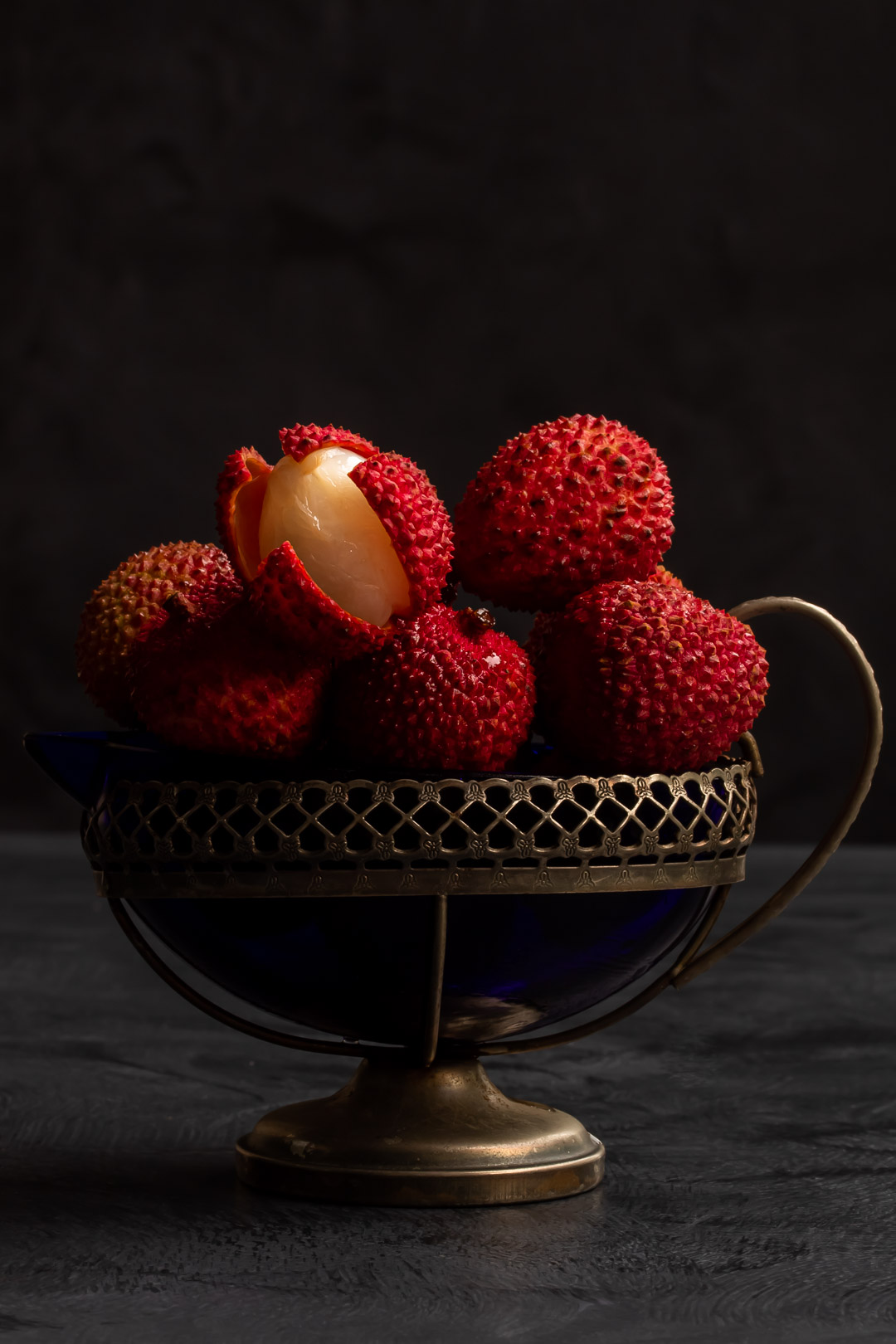 fresh lychees in vintage cream jug for lychee reviver cocktail with one peeled to reveal white fruit