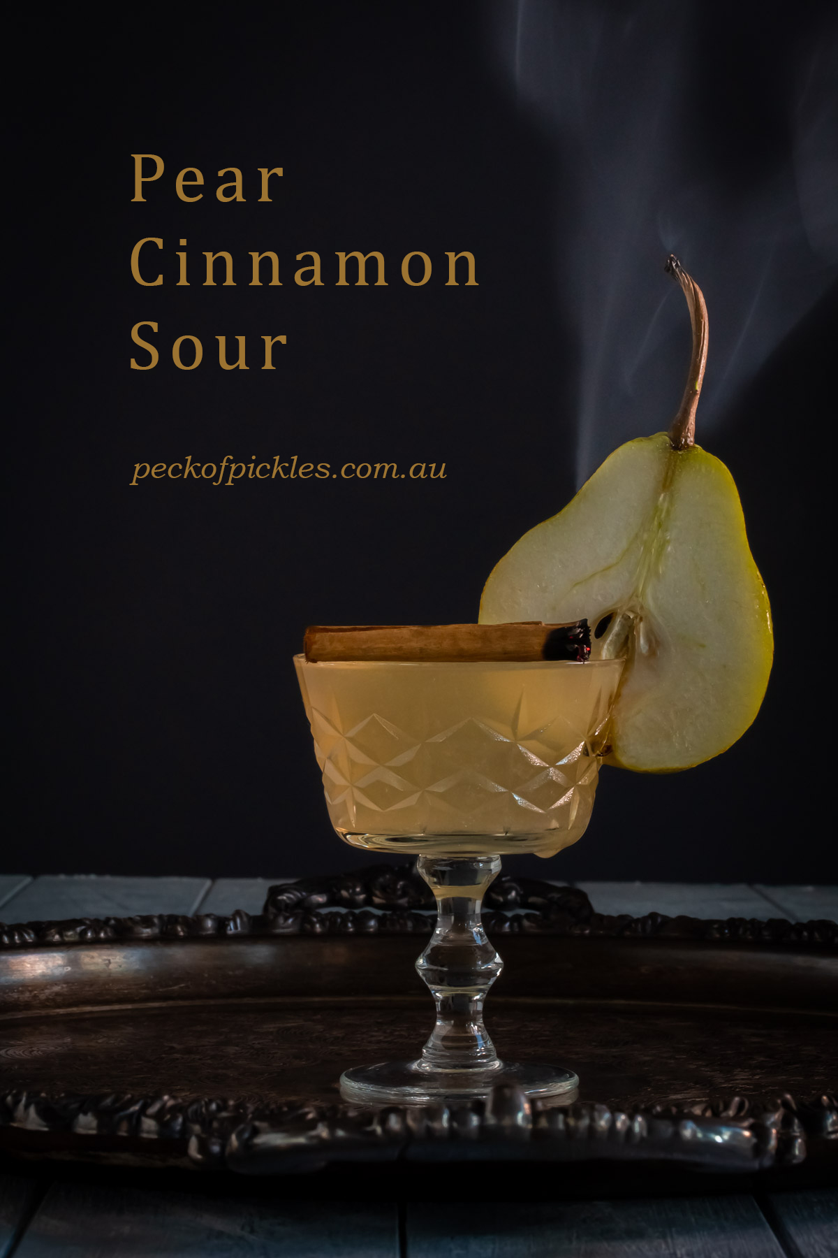 pear cinnamon sour on silver tray with pear slice and cinnamon smoke