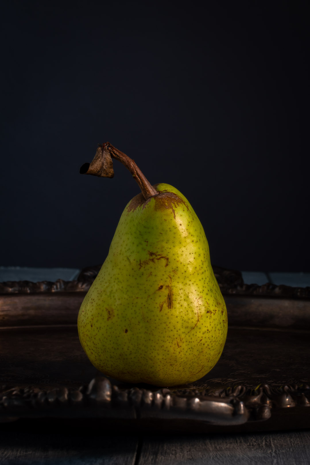 single pear on silver tray with withered leaf for pear cinnamon sour