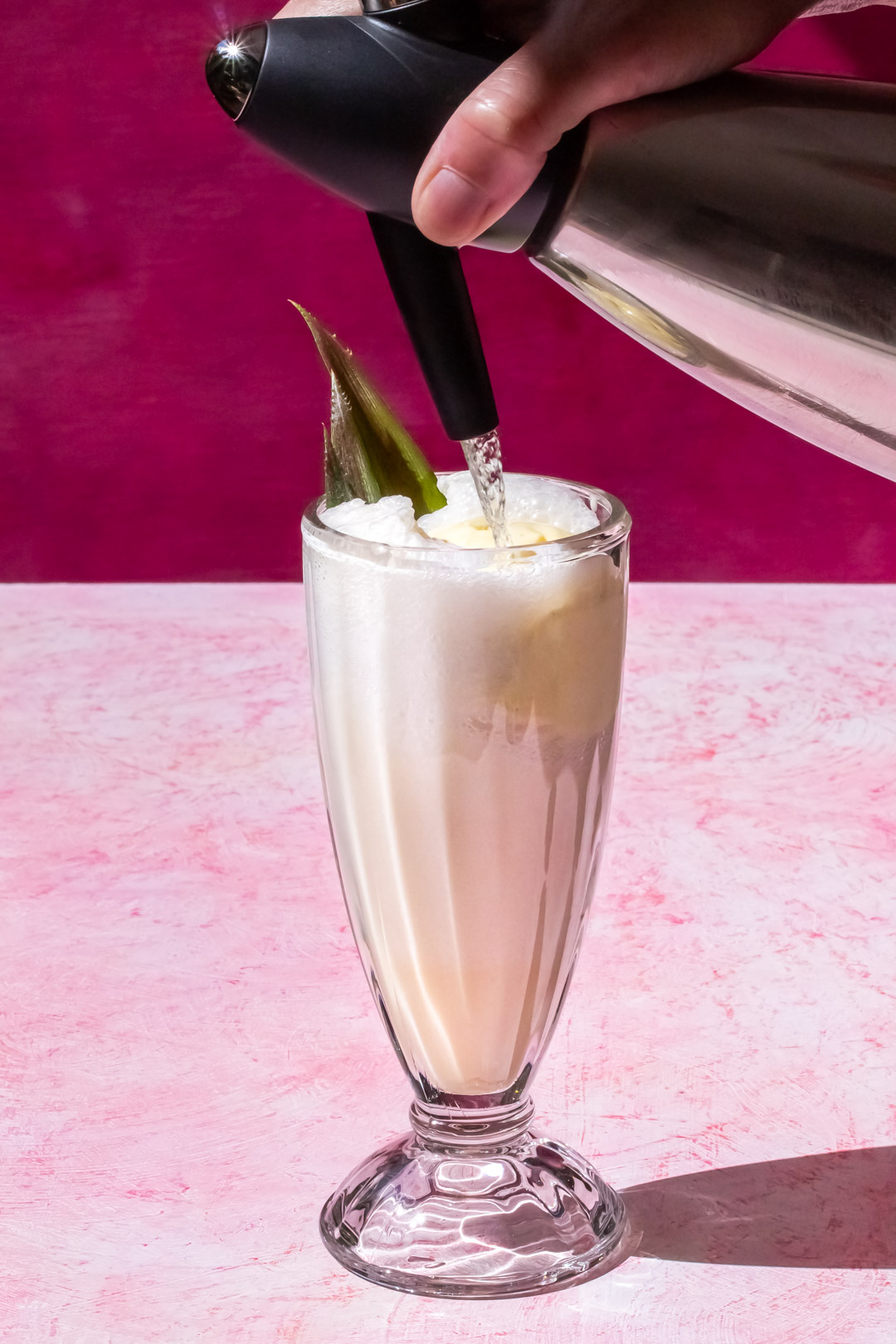 foaming pineapple pistachio cream lactart with a fine stream of soda using a soda siphon