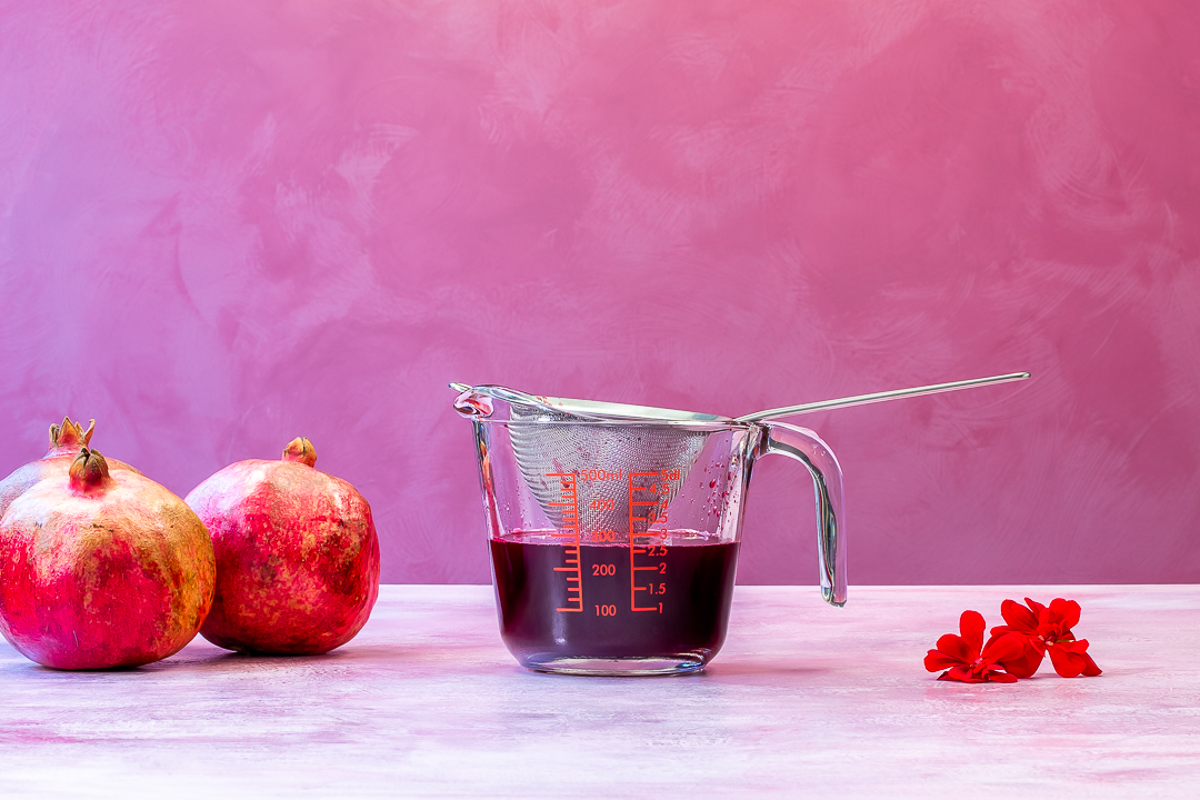 pomegranate juice with pomegranates and geranium flowers