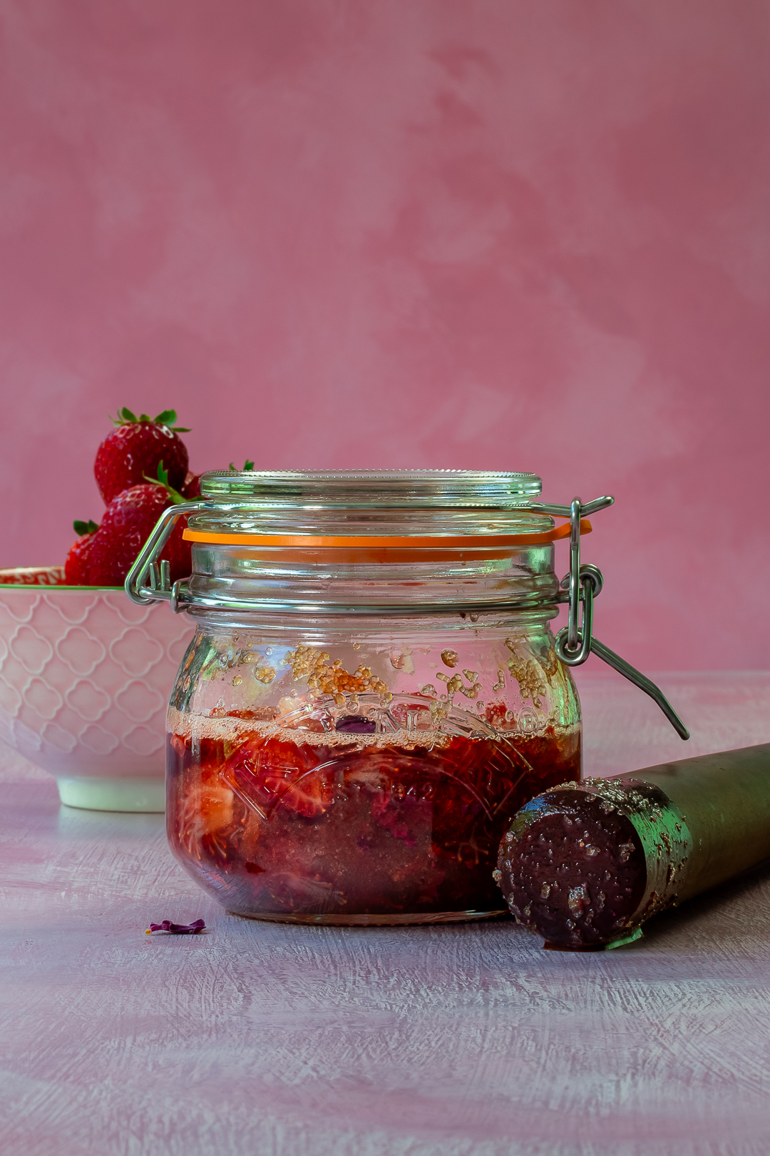 kilner jar with strawberries, demerara sugar and petals macerating for use in strawberry syrup for strawberry tequila collins