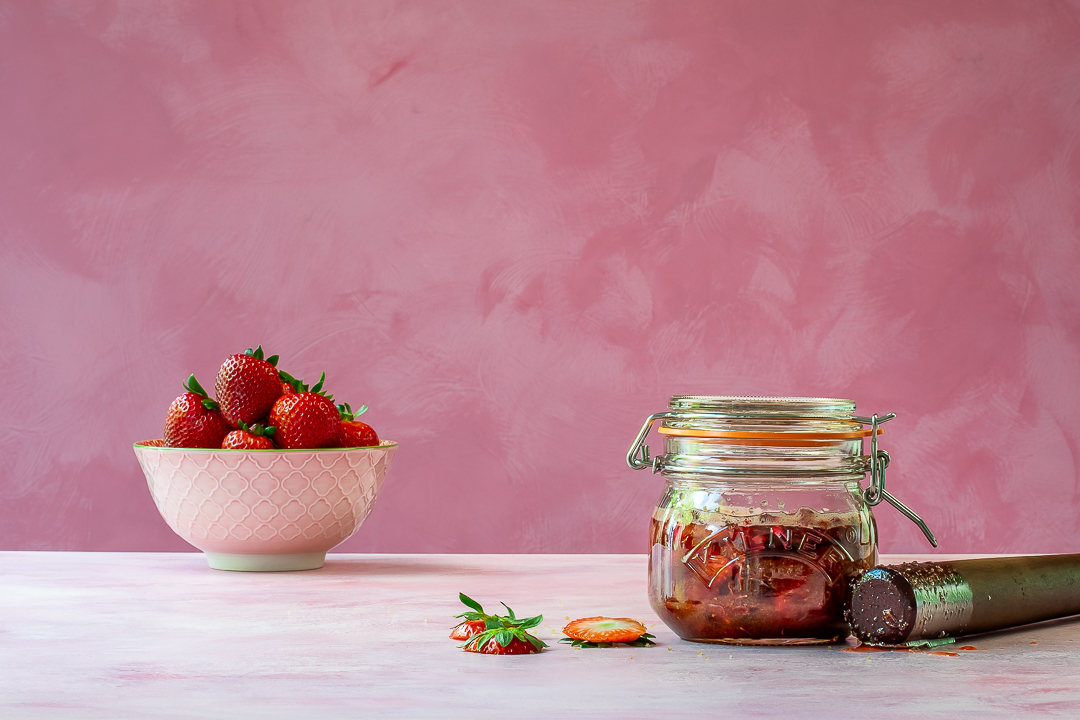 muddled strawberries, rose petals, hibiscus flowers and demerara sugar in kilner jar for making strawberry syrup for use in strawberry tequila collins