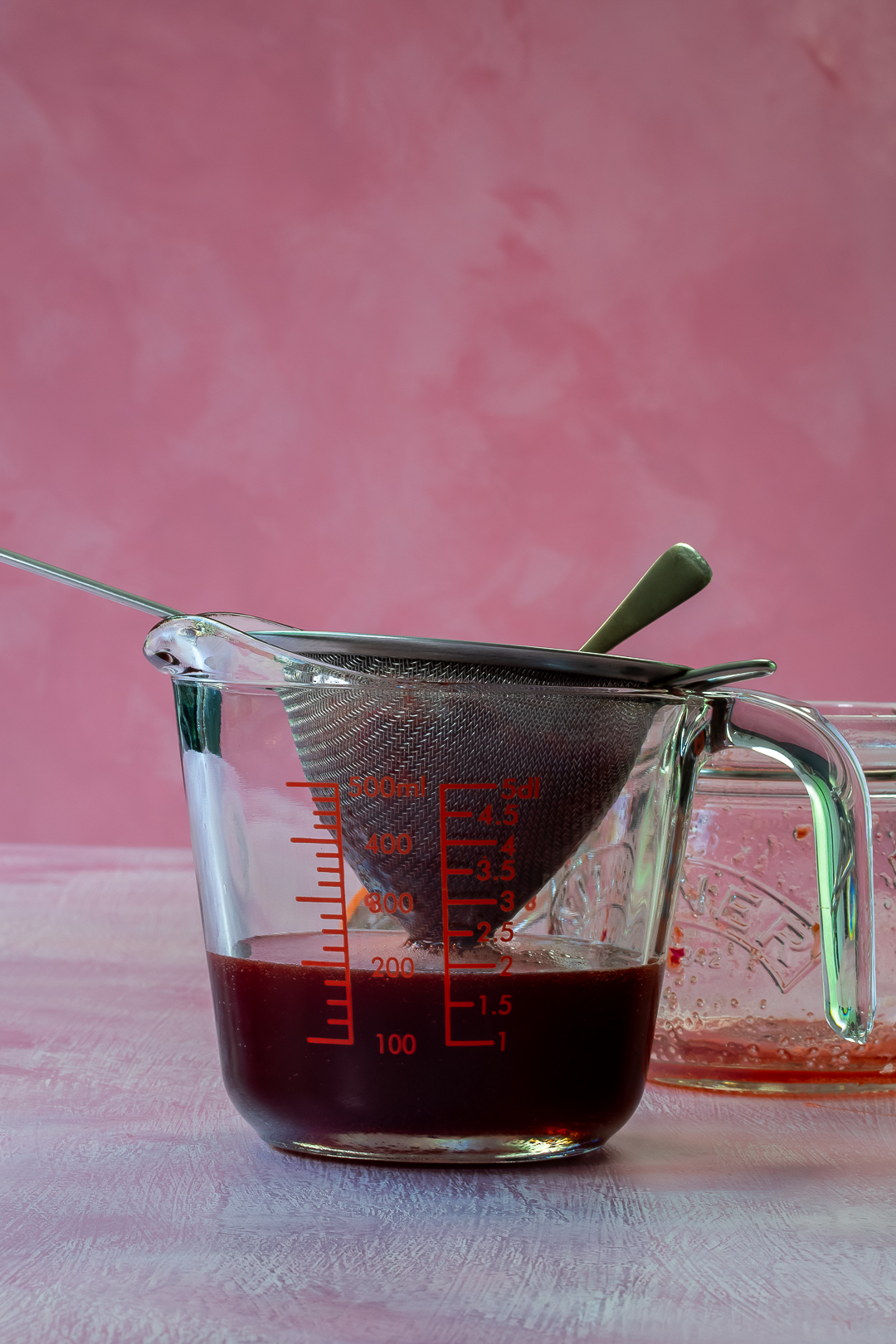 strained strawberry syrup in a jug for use in strawberry tequila collins