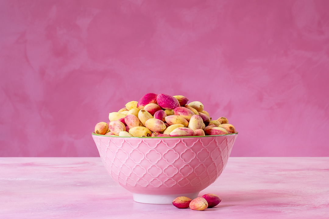 pistachios in dish horizontal with three pistachios in front for making pistachio syrup for use in pistachio limeade